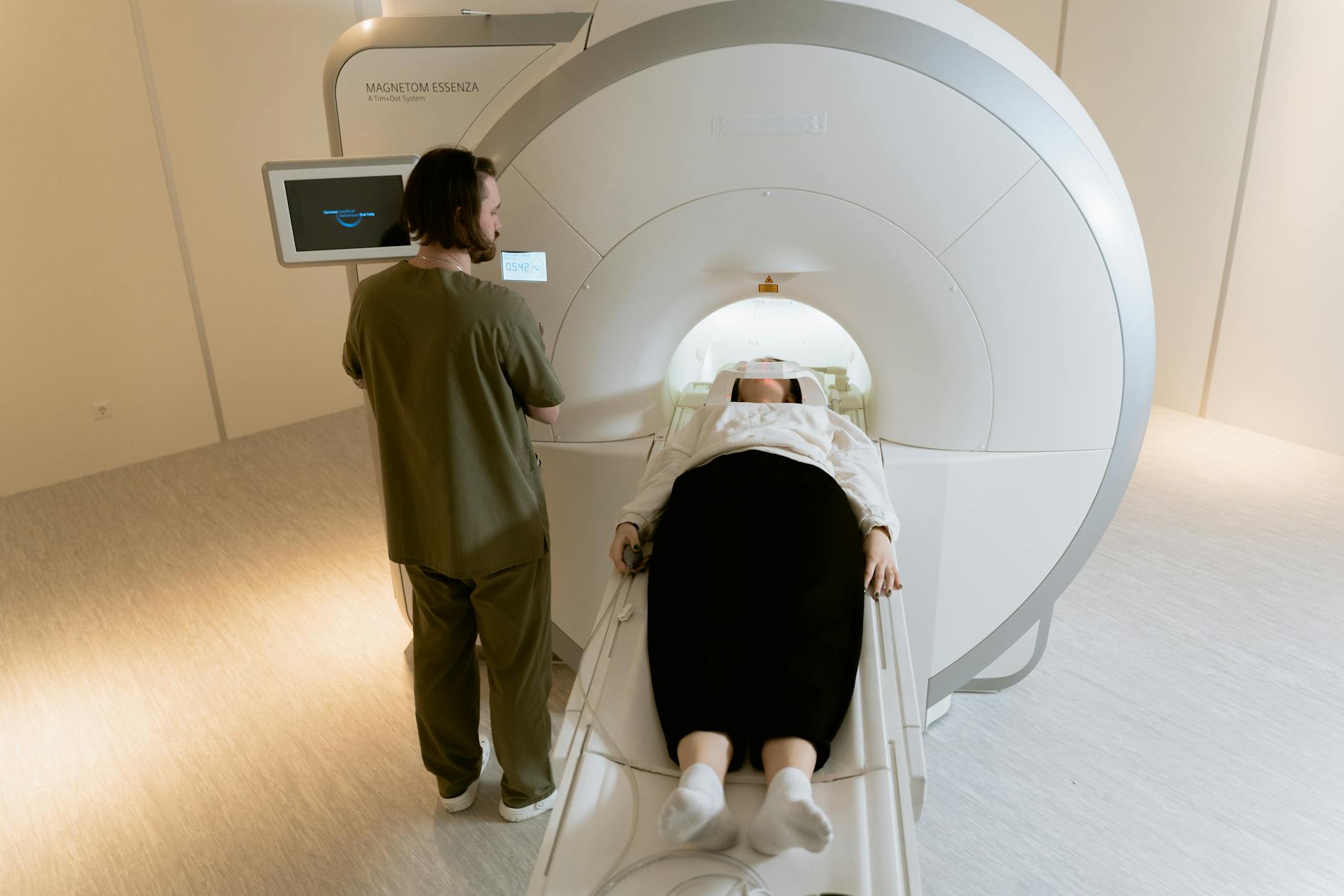 A patient undergoing an MRI scan with a healthcare professional present in a modern medical facility.