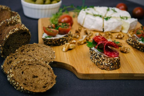 Free Slices of Bread with Seeds Topped with Salami on a Wooden Chopping Board Stock Photo