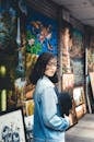 Asian woman standing with hat in hand near paintings