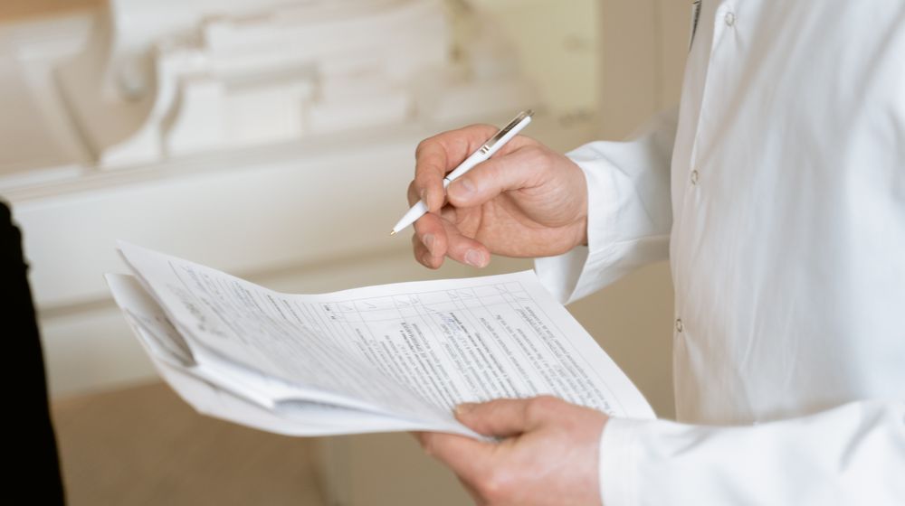 A doctor holds and reviews medical documents, demonstrating careful examination and professionalism.