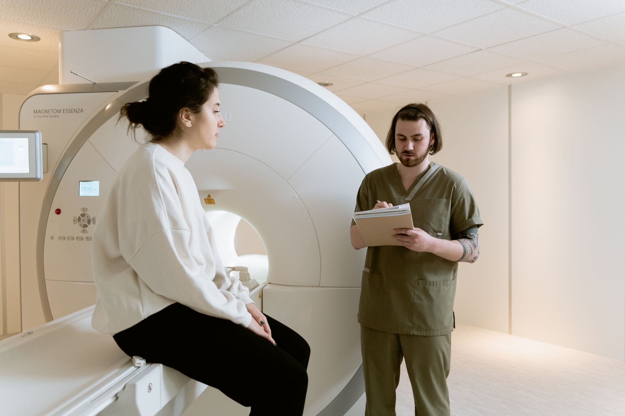 Healthcare technician with a patient beside an MRI scanner