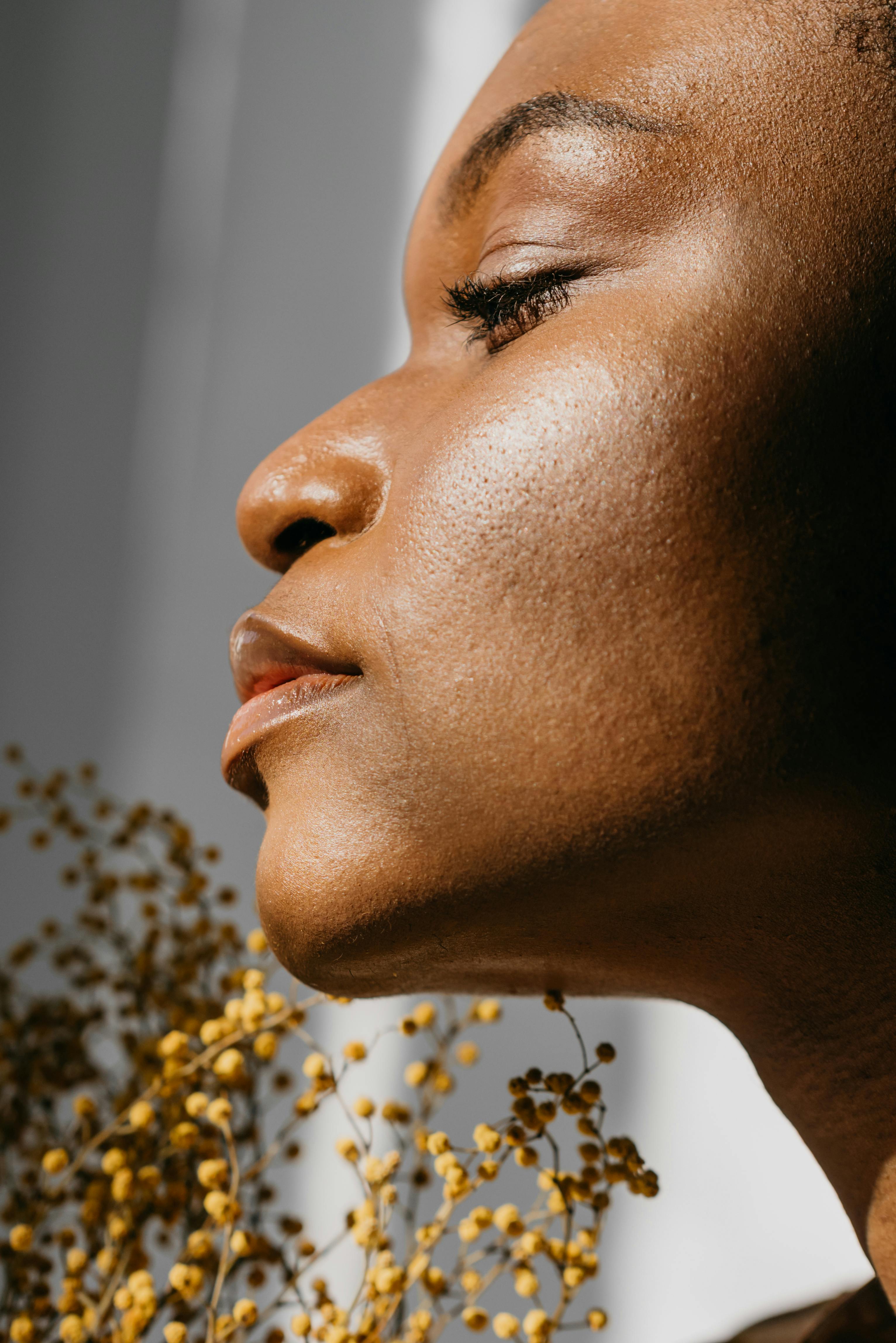 Close-up side view portrait of a woman in natural lighting, showcasing fresh skin with soft, blurred background.