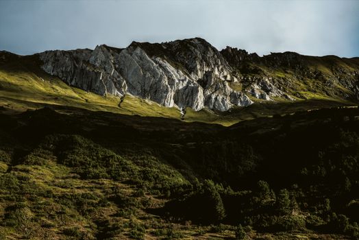 A stunning view of mountain peaks with rich greenery beneath, under a clear blue sky.