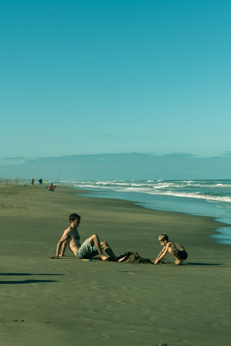 A Father And Son Playing Sand On The Beach