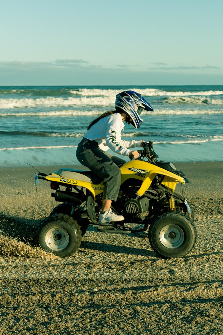 A Person Wearing Helmet While Riding An Atv On The Beach