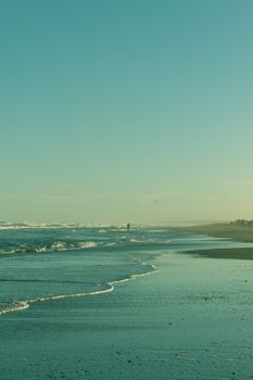 A tranquil beach scene with gentle waves under a clear blue sky, perfect for relaxation and calm.