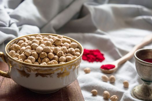 Close-up of a decorative bowl filled with chickpeas, surrounded by spices, creating a rustic kitchen scene.