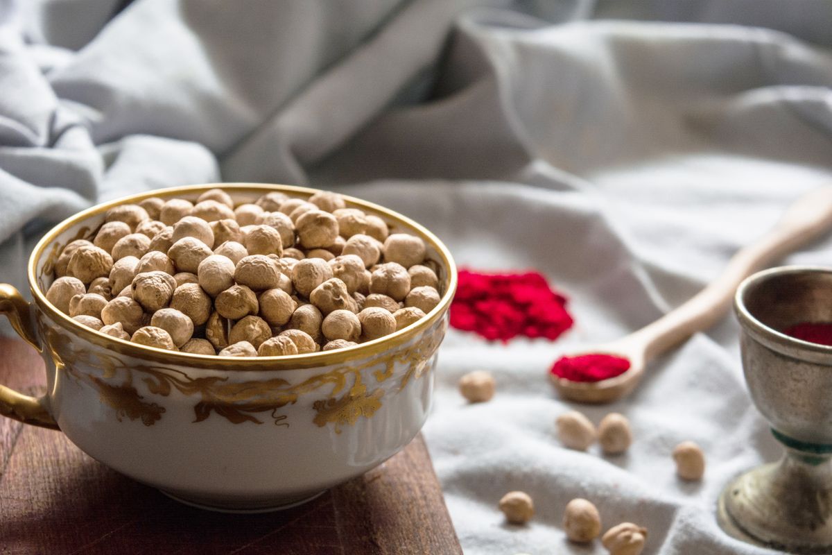 Close-up of a rustic bowl filled with dried chickpeas surrounded by spices, a source of galacto-oligosaccharides and resistant starch