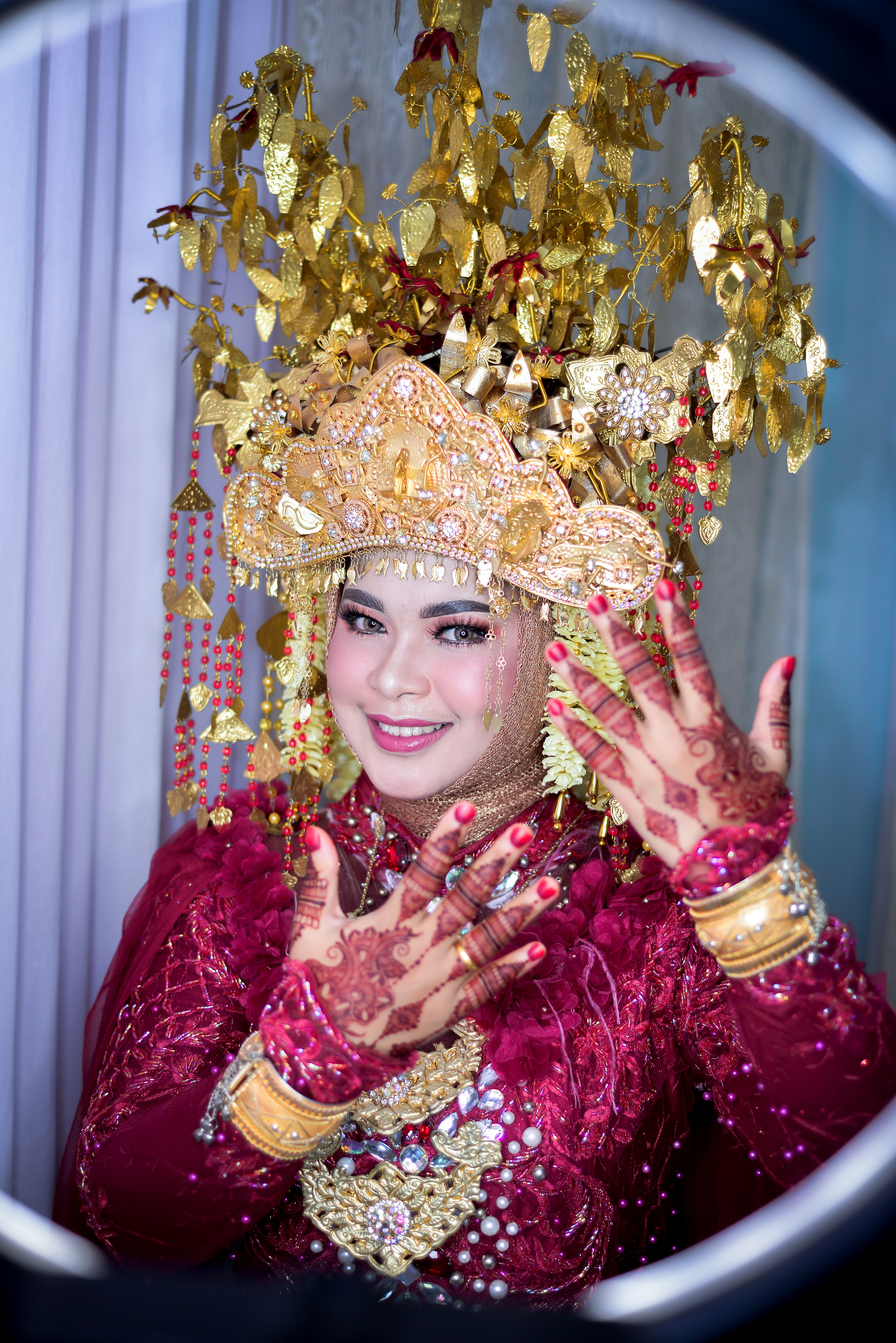 Smiling bride in ornate headdress and traditional Southeast Asian attire.