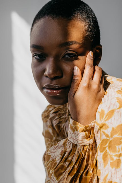 Free A Shaved Head Woman with Her Hand on Her Face Stock Photo