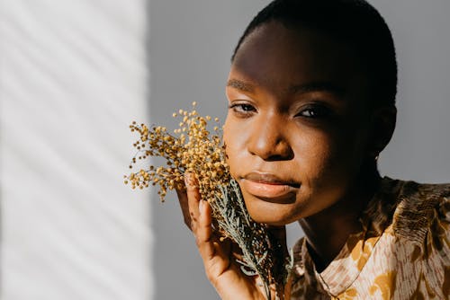 Free A Woman Holding Flowers Near Her Face Stock Photo