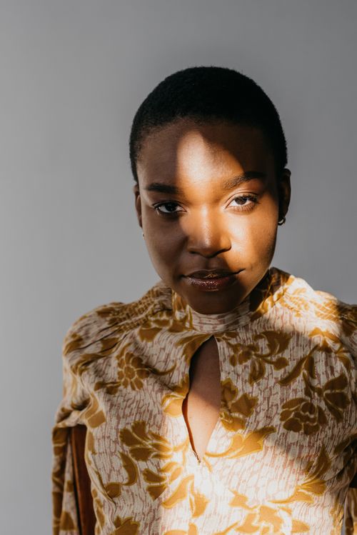 Free Close-up portrait of an elegant woman in a floral top with dramatic sunlight. Stock Photo