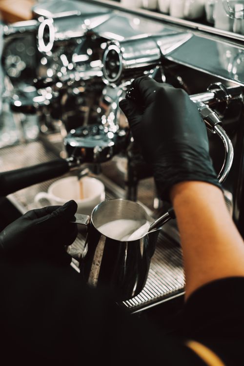 Free Close-up of a barista steaming milk at a coffee bar with a stainless steel espresso machine. Stock Photo