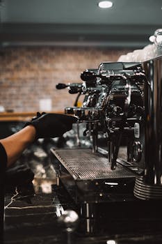 A barista in black gloves operates an espresso machine in a modern coffee shop.