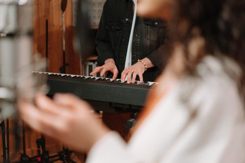 Free Close-up of hands playing a keyboard in a cozy recording studio setting. Stock Photo