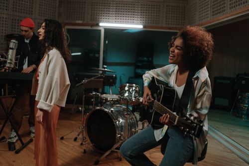 Free A diverse band passionately rehearsing with instruments in a modern music studio. Stock Photo