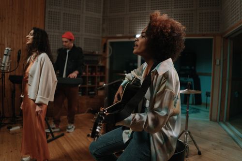 Free Group of musicians playing in a cozy music studio. Includes guitarist, singer, and keyboard player. Stock Photo