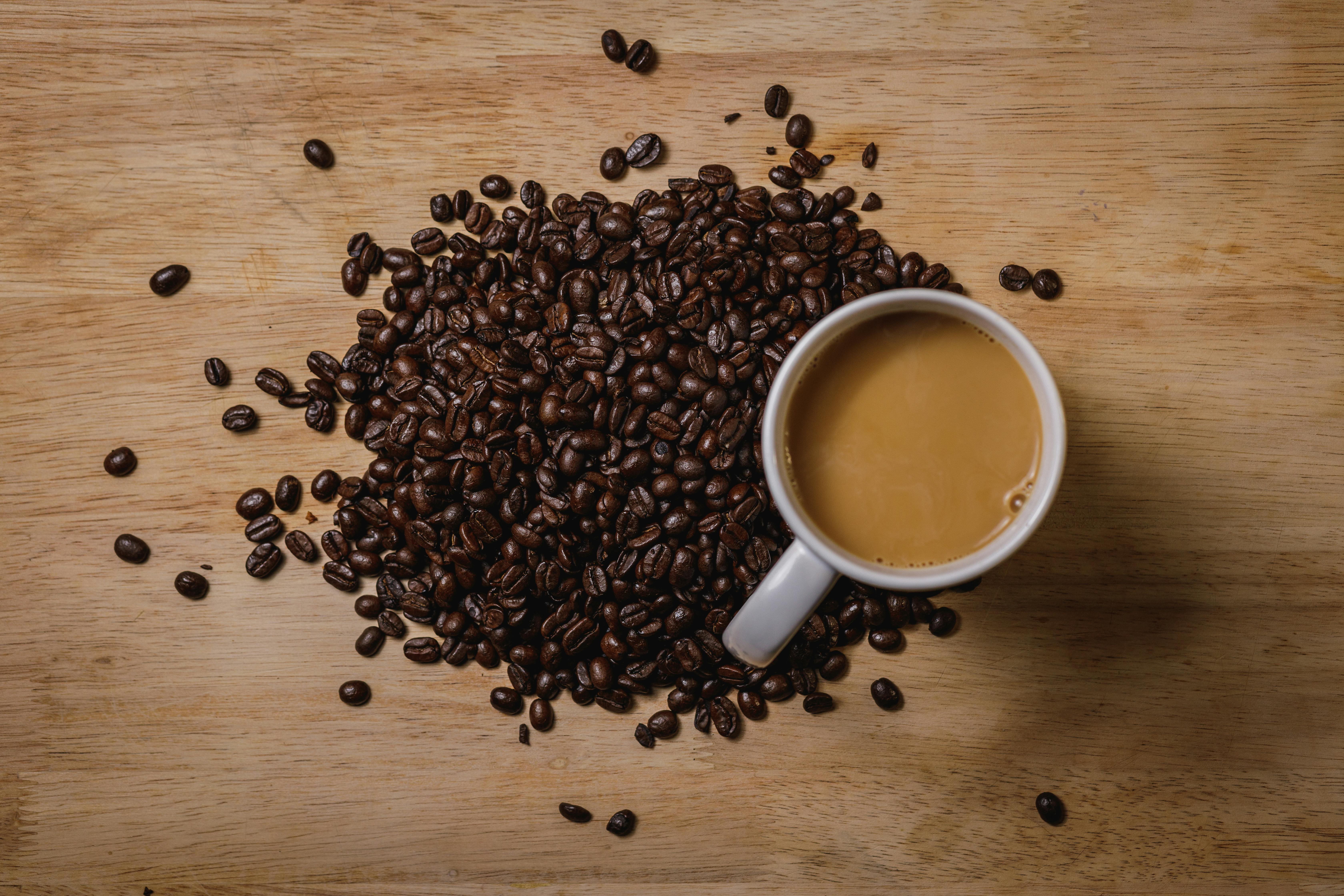 Aesthetic arrangement of coffee beans and a cup of coffee on a wooden surface.