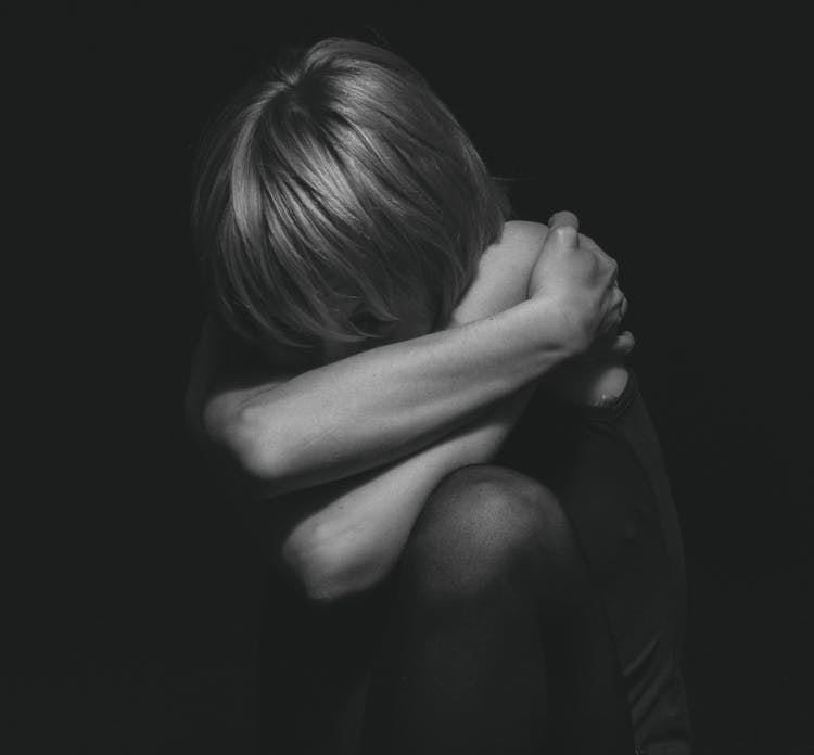 Grayscale Photo Of A Person Hugging Self