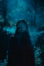 Dead female with bullet wound on forehead in haze at dark night in woods