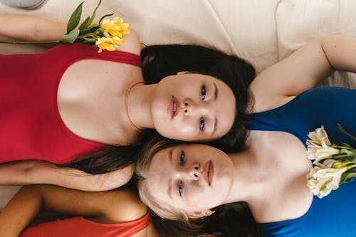 Women Wearing Swimsuit Lying on the White Textile