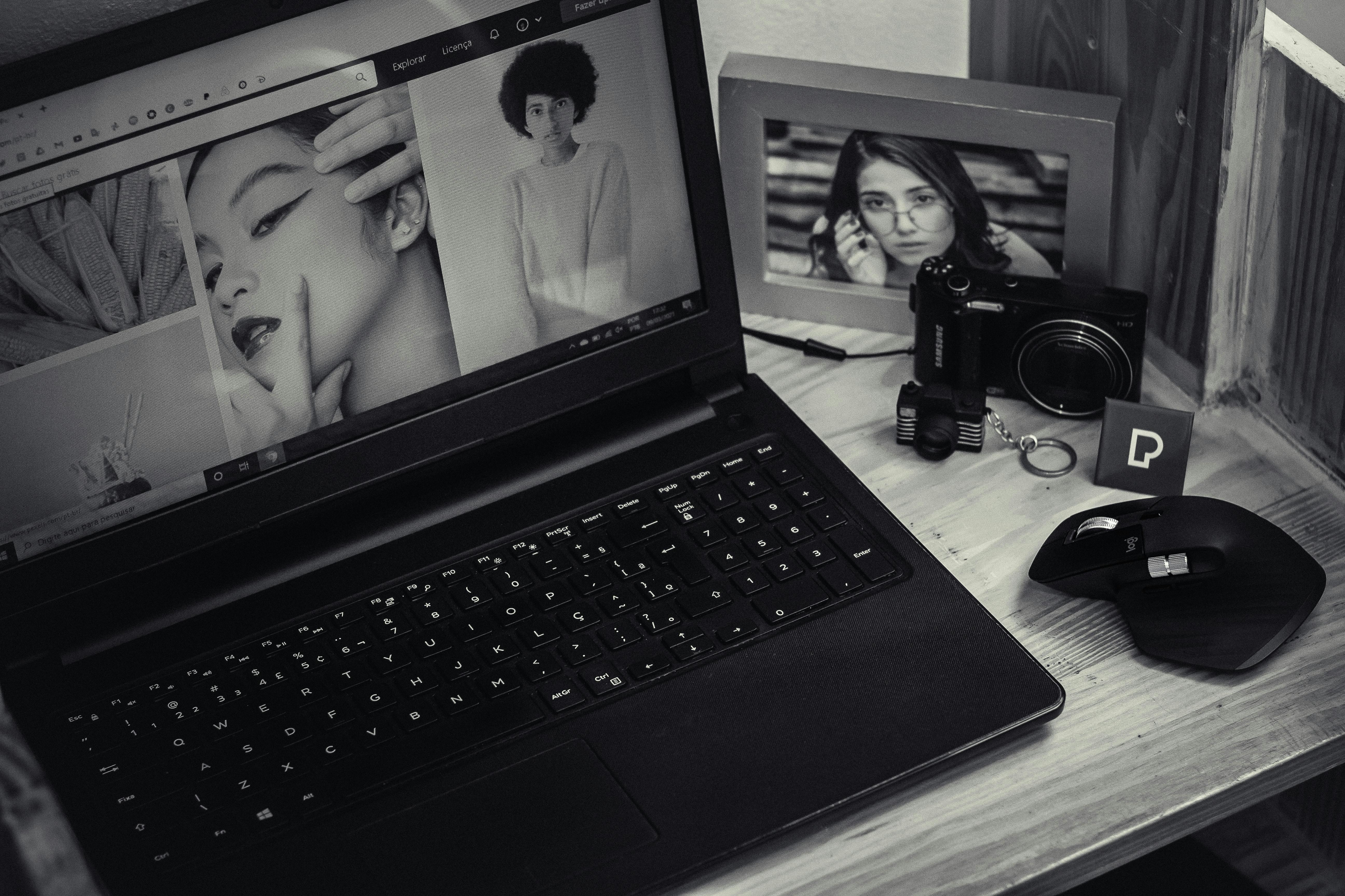 modern laptop with photos on screen near photo camera