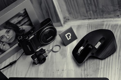 Modern photo camera near black game mouse