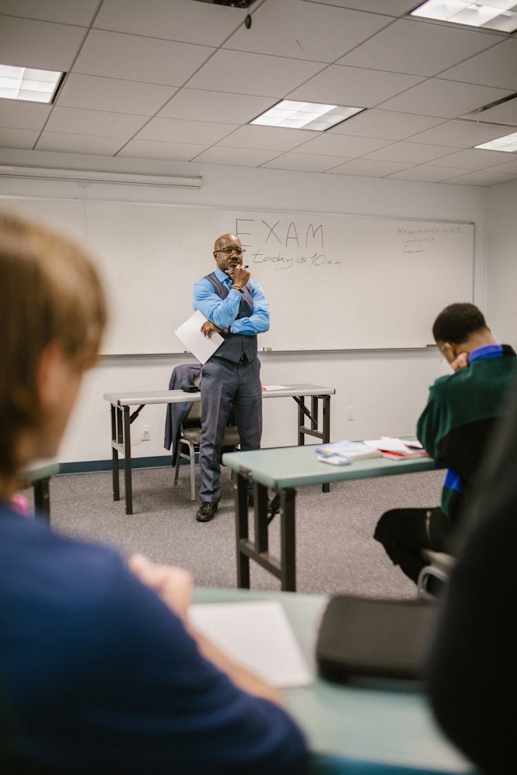 Teacher Proctoring His Students During An Examination