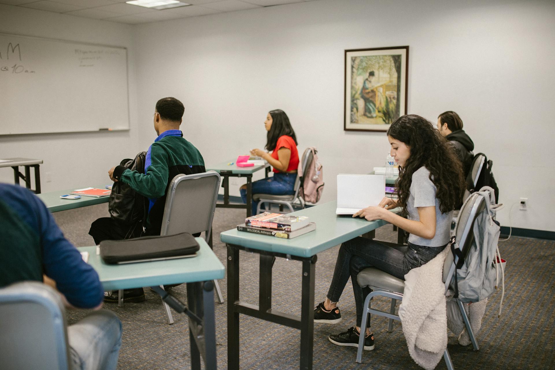 Students engaged in study inside a college classroom with books and discussions.