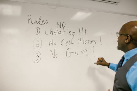 A teacher writes important classroom rules on a whiteboard in a college setting.