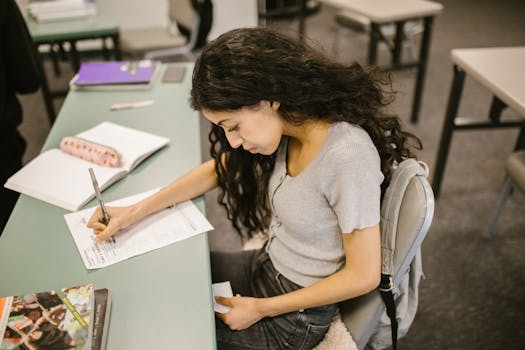 Young college student writing on test paper in a classroom setting, focused on academic success.