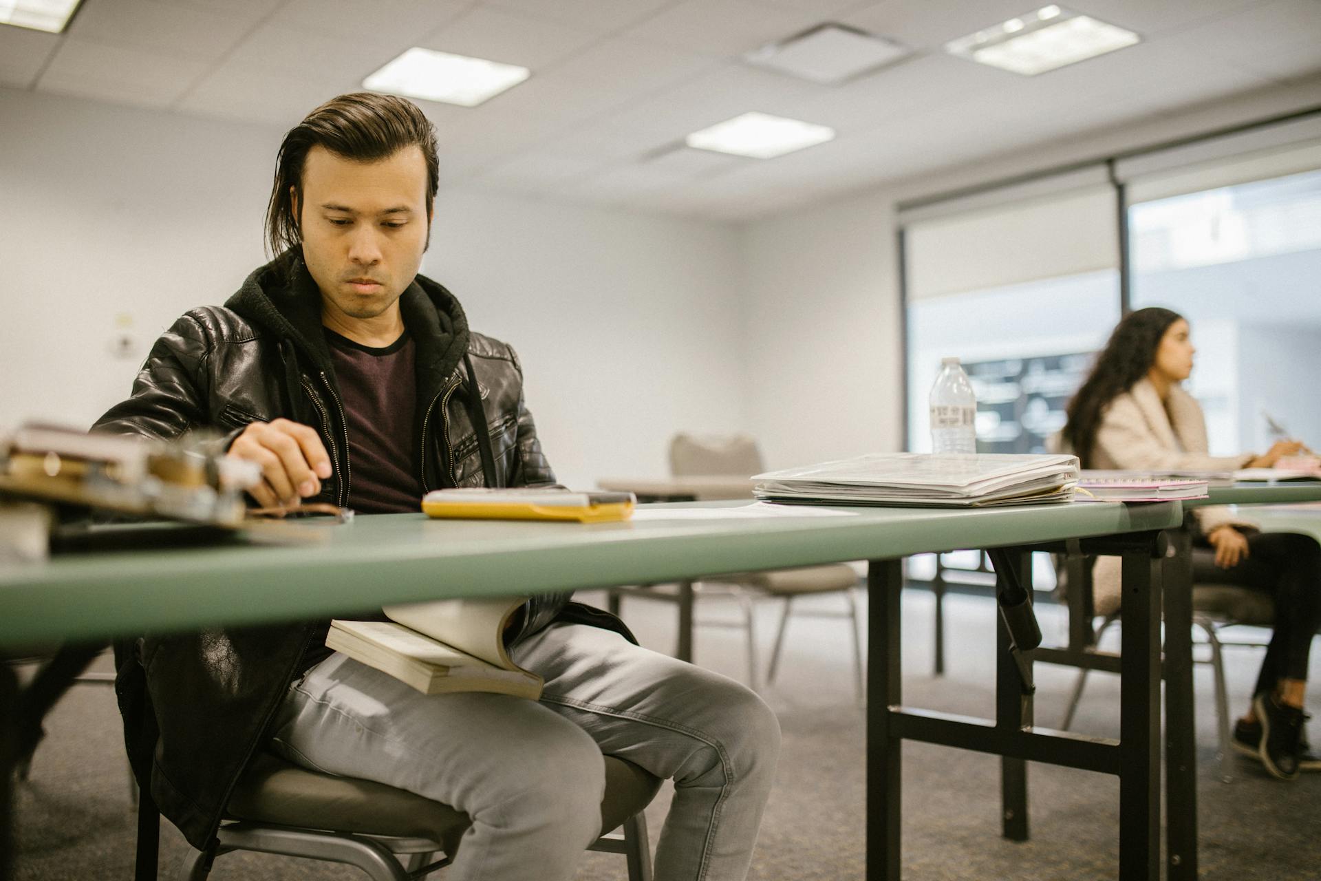 Two college students engaged in focused study at a classroom desk, preparing for exams.