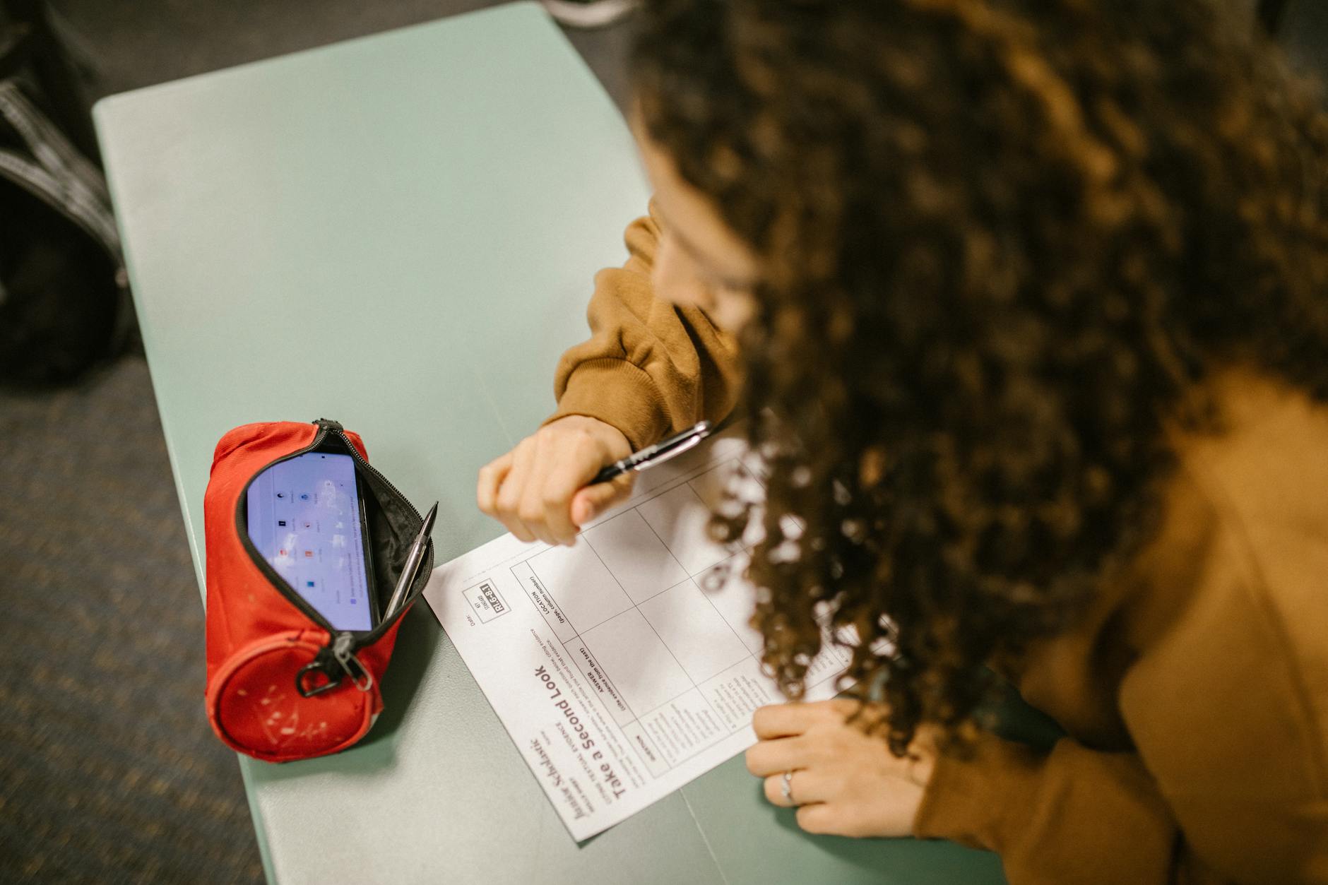 A student using a smartphone hidden in a pen case during an exam.