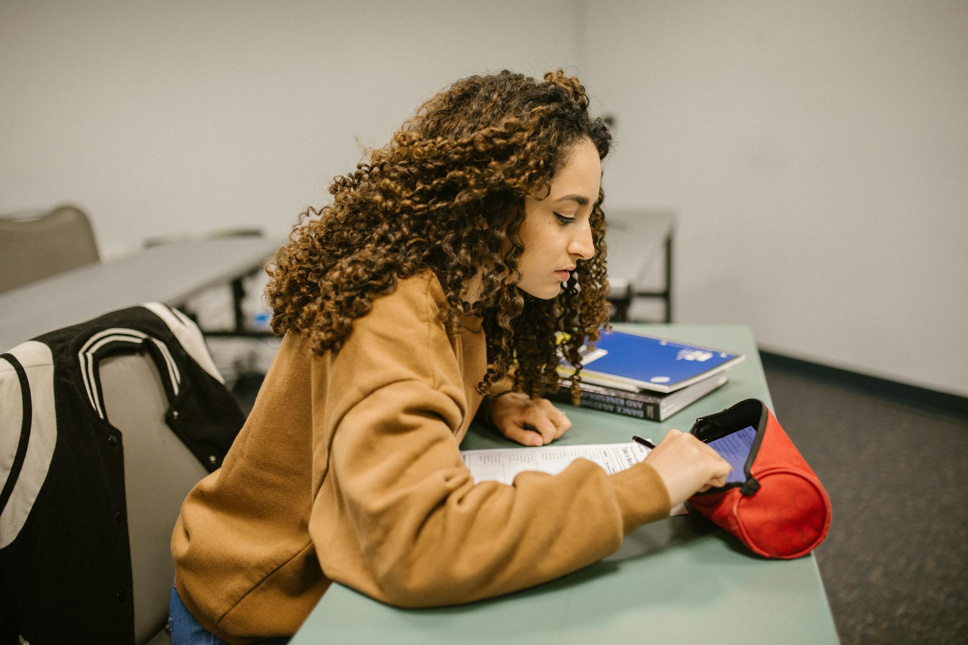 A college student secretly using a cheat sheet during an exam in a classroom.