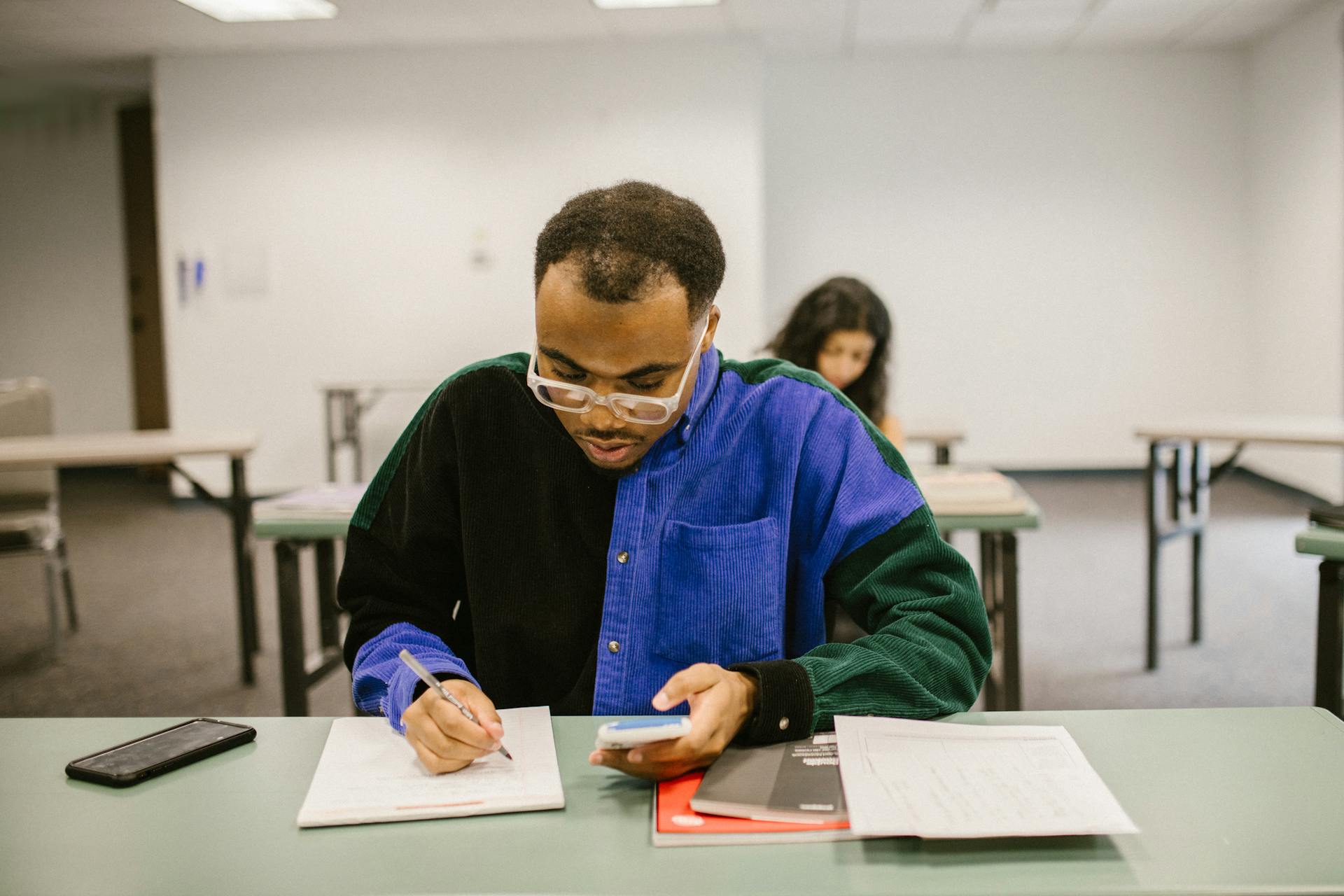 Focused college student with calculator and notes during classroom examination.