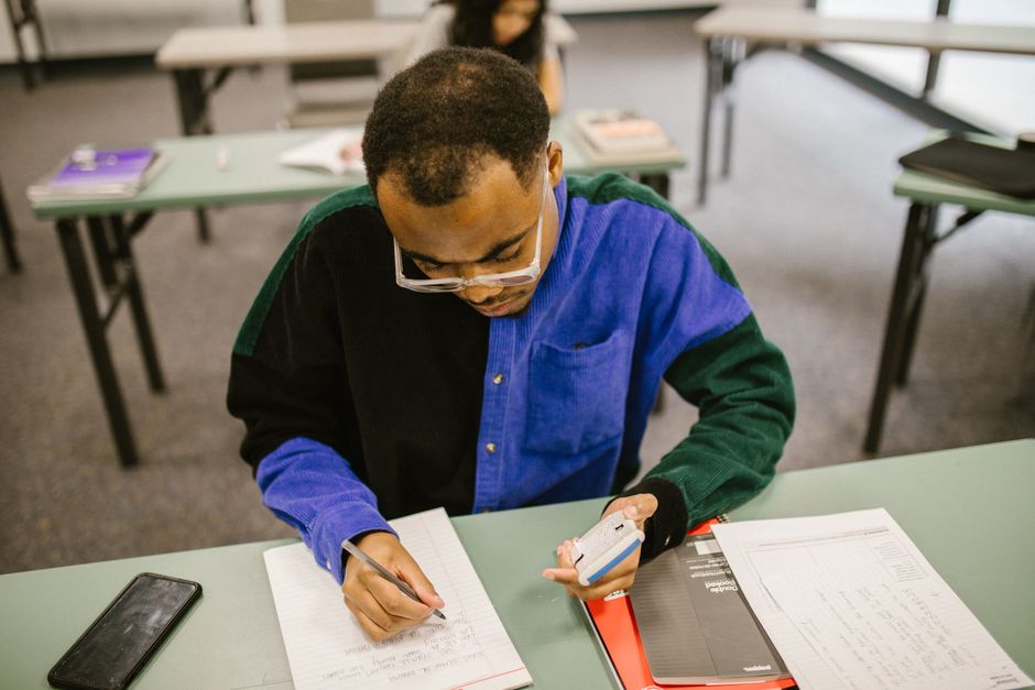 College student writing notes at a classroom desk, studying for an exam. College student writing notes at a classroom desk, studying for an exam.