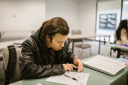 A man concentrating on an exam paper in a classroom setting, emphasizing education.