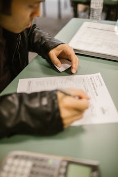 A student attempting to use a cheat sheet during a test in a classroom setting.