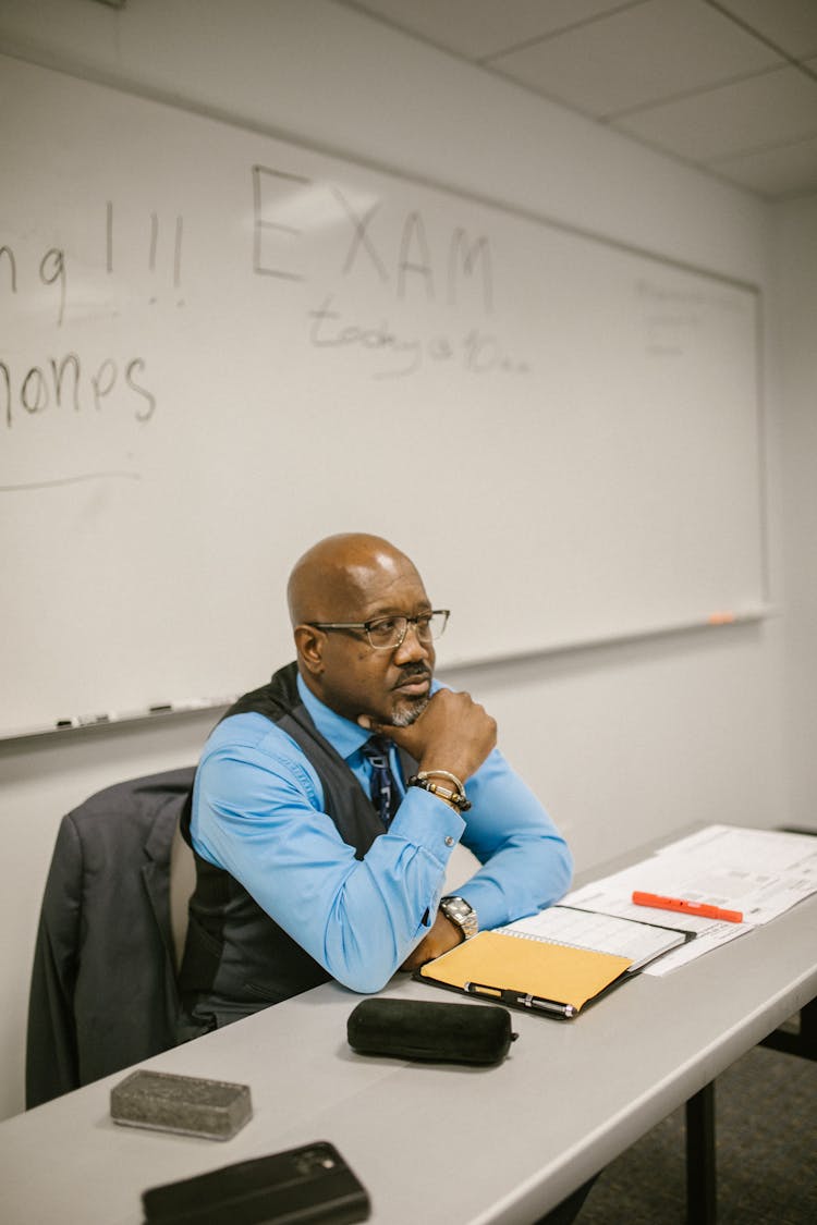 Teacher Sitting By His Desk