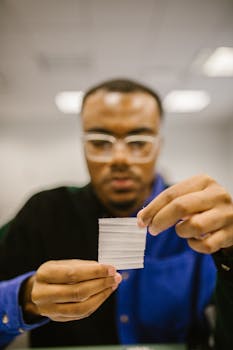 A student examining a small note during a class session, possibly for an exam.