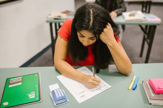 A focused college student studying at her desk during an exam preparation session.