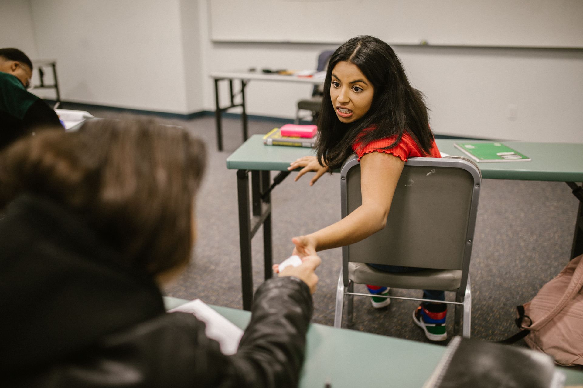 Students sharing notes during an indoor college class in a playful setting.