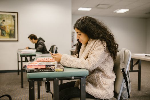 Female college student focusing on study materials in a classroom setting.
