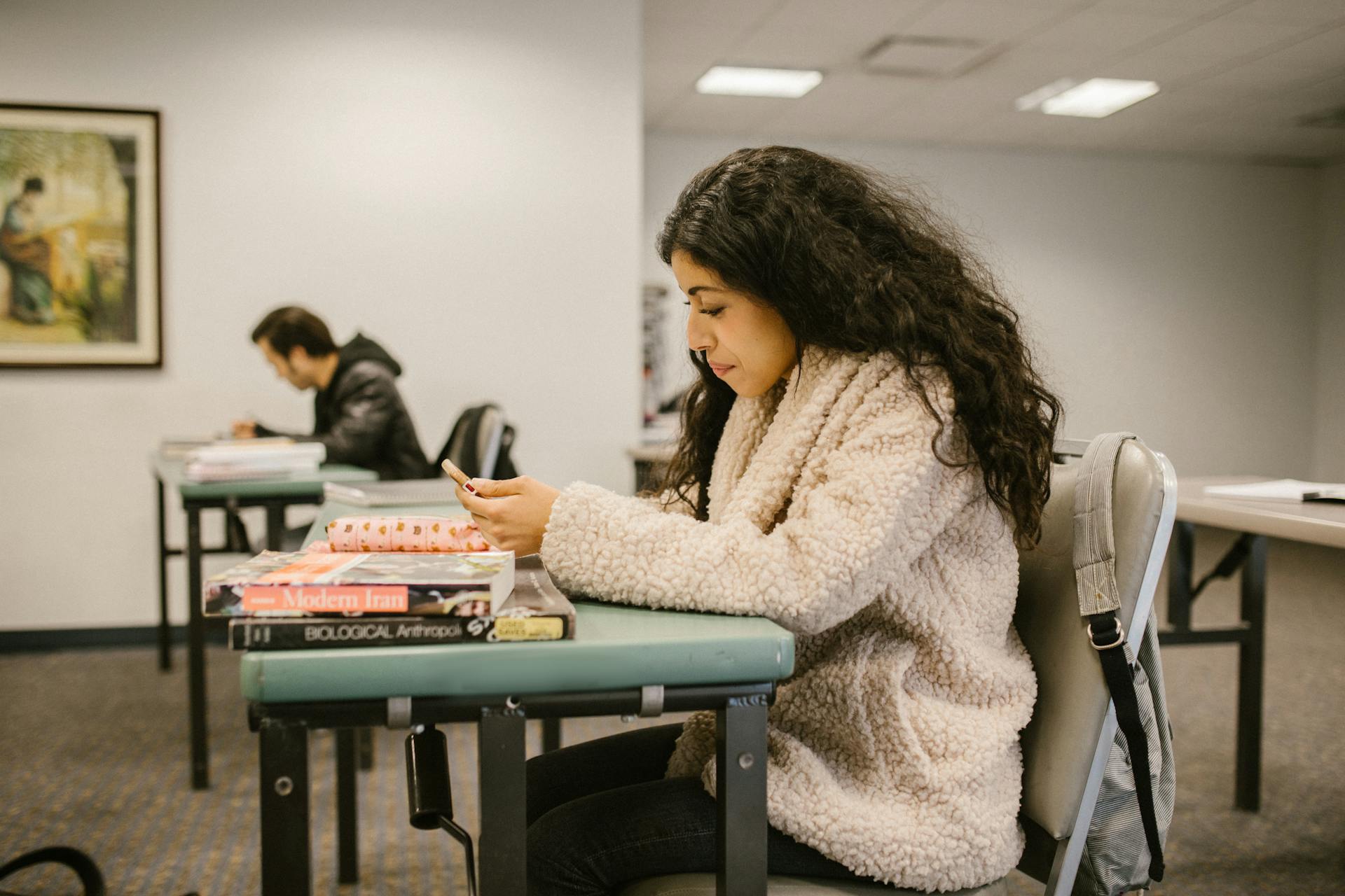 Female college student focusing on study materials in a classroom setting.