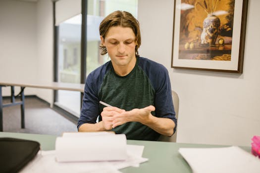 A man secretly uses a cheat sheet on his hand while studying indoors.