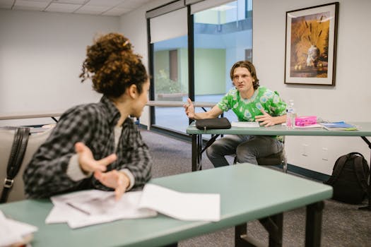Two students actively discussing ideas in a college classroom setting.