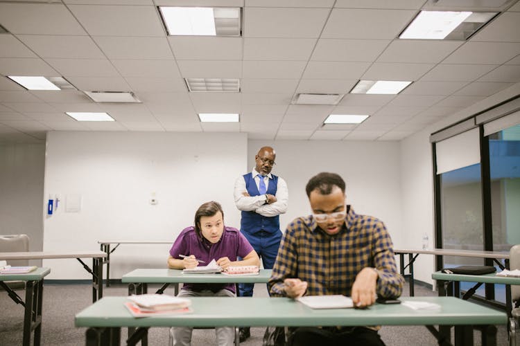 Teacher Proctoring His Students During An Examination