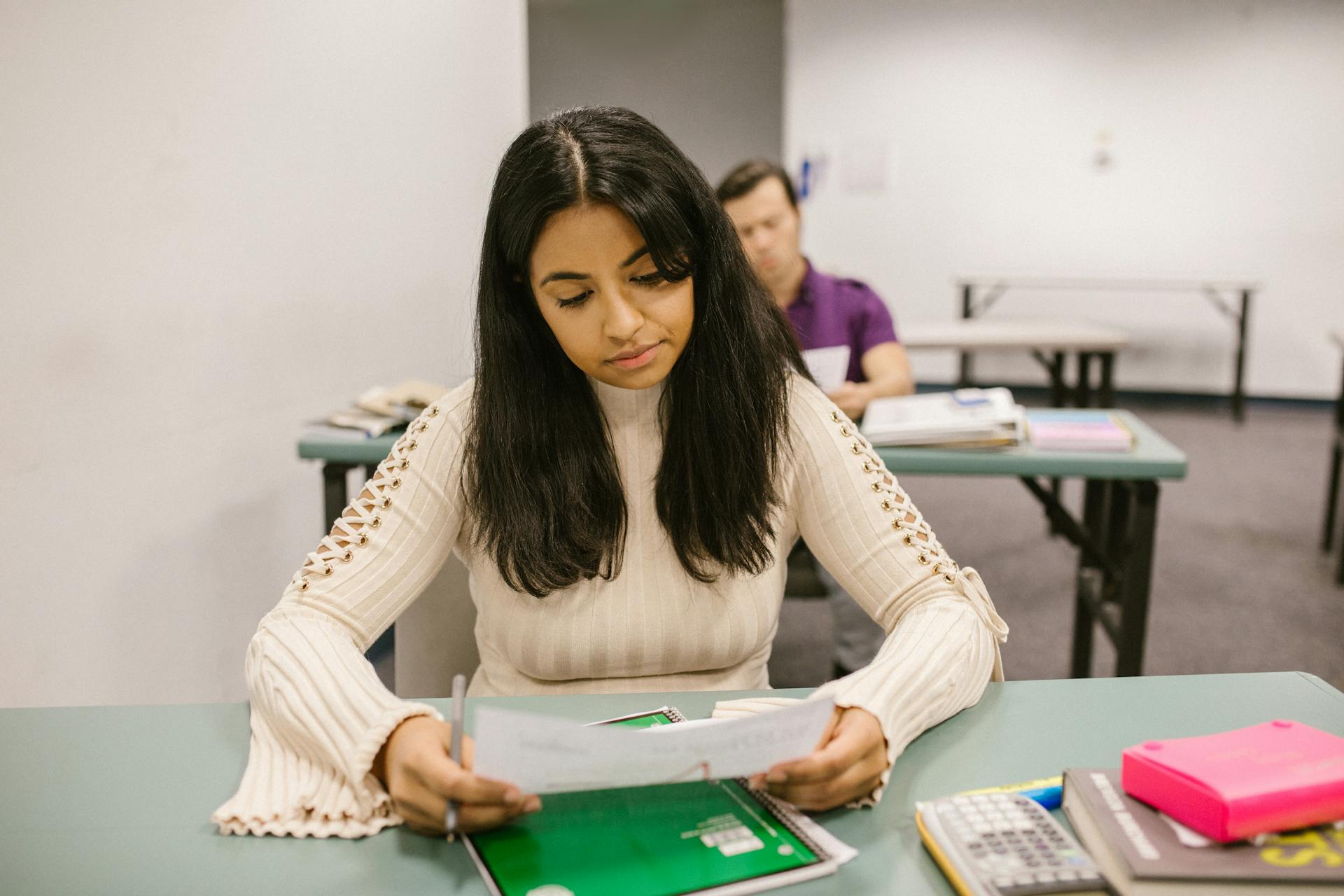 Female college student looking at exam results in a classroom setting, focused and thoughtful.