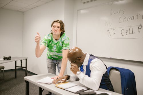 Free Student Signaling His Classmates to Cheat During an Exam Stock Photo