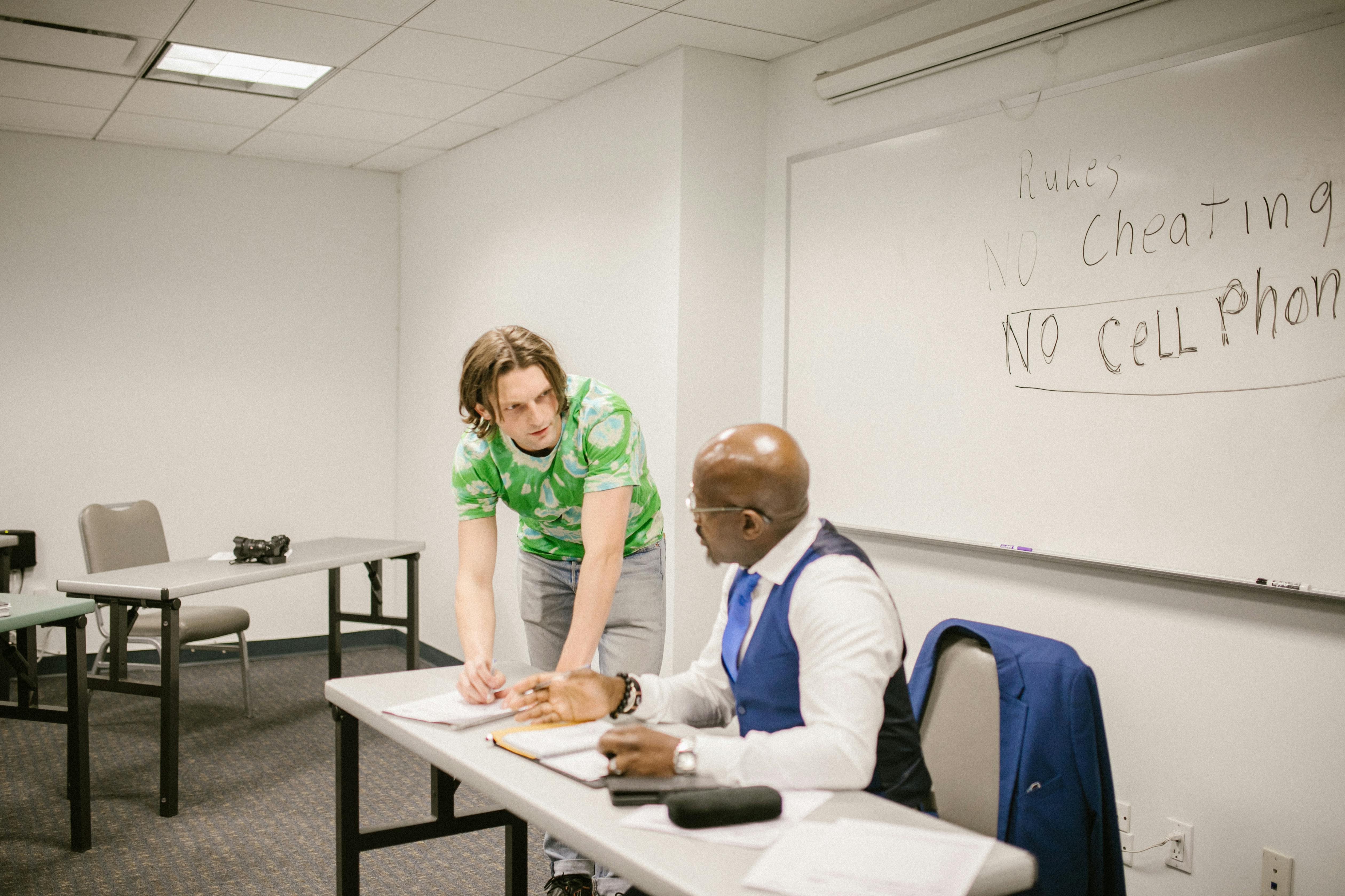 A teacher and student discuss exam rules in a modern classroom setting.